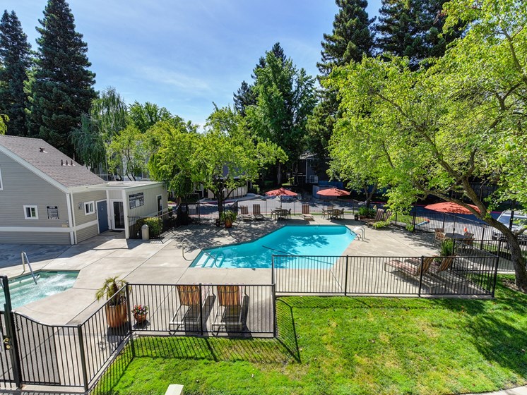Upper View of Pool Area with Grass, Gates and Orange Patio Umbrellas